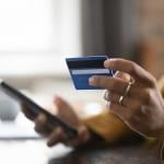 Female customer using a credit card and checking a phone.