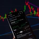 The AstraZeneca stock graph displayed on a mobile phone with other stock charts in the background.
