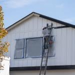 A house painter doing trim work of a house's exterior wall. 