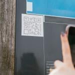 User scanning a QR code on a wall with a phone.
