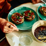 Plates of special bagels and a healthy oat meal served on a table.