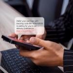 Person using phone with an illustration of an SMS bubble showing potential scam with phishing link.