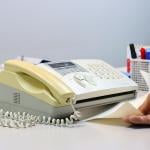 Person feeding a yellowing fax machine paper.
