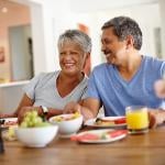 A retired senior couple happily having breakfast at home.