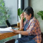 A senior small businesswoman reviewing reports by the window of her store.
