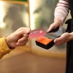 A person paying with a credit card payment machine held by a cafe staff.