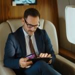 A business executive shopping online while traveling from a private jet's cabin.