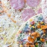 Multiple frozen pizzas wrapped in plastic stacked on each other