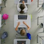 Ceiling view of students working on projects on their laptops inside the classroom.