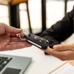 A person returning a car key to an employee for completing a car rental service.