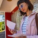 A young woman checking letters from mailbox.