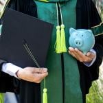 A person wearing a bachelor uniform holding a cap and a piggy bank.