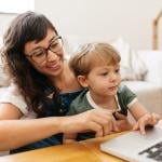 A mother and a son checking on a laptop in a living room.