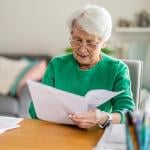 A senior woman sitting in the living room and doing paperwork.