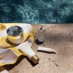 Skincare items in a towel next to a swimming pool. 