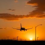 An airplane landing at Los Angeles International Airport during sunset in California, USA.