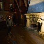 Cameron Jensen standing inside one of his newly acquired buildings in Logan Canyon in front a fireplace illuminated by a floor lamp.