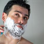 A young man shaving his beard.
