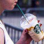 A person drinks Starbucks iced coffee outside.