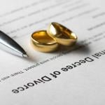 Marriage rings and a pen on top of a divorce decree form. 