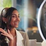 A young female influencer filming a vlog at home using a ring light and smartphone.