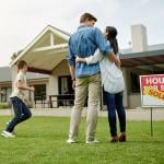 A family of four celebrating on the yard of their new home.