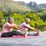 Two elderly women stretching their bodies during an outdoor yoga.