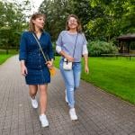 Two friends sharing stories while strolling in a city park. 