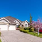 A multi-car garage residential property with a for sale sign.