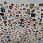 Olympic enamel pins from different countries arranged on a white board showcasing.