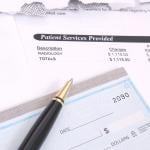 Medical bill statements and a check with a pen.