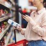 A person scanning a QR code of a product from her smartphone in a supermarket.
