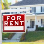 A For Rent sign placed in front of a residential house.