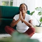 A elderly person practicing meditation in a prayer pose during a yoga session.