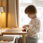 A young boy playing with block toys in the corner of a room.