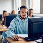 A male university student using a desktop computer during a class.