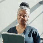 A female HR professional looking confused while reading information from a tablet.