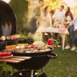 A focus on a barbecue grill set outdoors, with a group of friends having a party in the backdrop.
