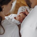 A couple staring at their newborn baby who is sleeping.