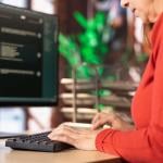 A female employee typing on a keyboard while working in an office.