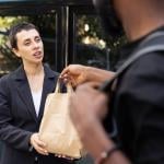 A food delivery person handing a customer's order.
