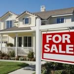 A For Sale sign in front of a residential house.