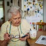 An elderly woman using a smartphone at home.