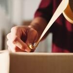 Person taping over a package for shipping.