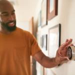 A man adjusting the thermostat at home.