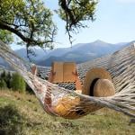 A person reading a book while relaxing in a hammock outdoors.