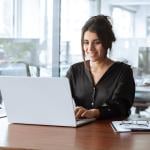 A focused young businesswoman working with a laptop in an office.