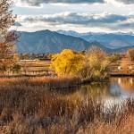Flatirons and mountain ranges seen behind the Stearns Lake in an autumn landscape in Broomfield, Colorado, USA.
