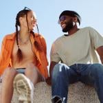 A couple bonding together while enjoying in a sitting wall outdoors.