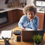 An entrepreneur reviewing budget, expenses, and payments of her business from a laptop.